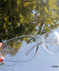 Person holding Clear Safety Glasses 24 Pack ANSI Z87.1 Impact Resistant Eye Protection UV400 against blue sky backdrop