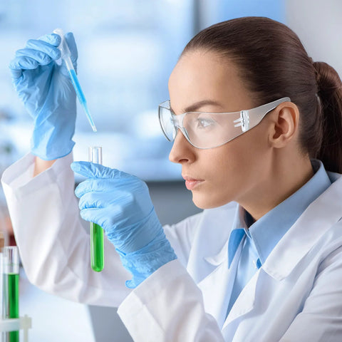 Scientist wearing 48 Pack Safety Glasses Clear Protective Eyewear For Work Lab Lightweight Comfort while conducting an experiment.
