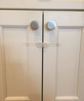 Installed self adhesive safety latch on cabinet doors, clear multi use straps for cabinets, fridges and freezers with four flaps.
