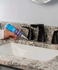 Person applying Clear Silicone Sealant All-Purpose Waterproof Adhesive 2.7 Fl Oz Tube for sinks on a bathroom countertop.