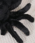 Close-up of Ultra Soft Black Spider Plush Toy For Kids And Adults, showing detailed plush fur and legs on a cream surface