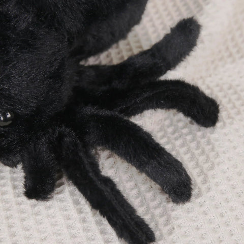 Close-up of Ultra Soft Black Spider Plush Toy For Kids And Adults, showing detailed plush fur and legs on a cream surface