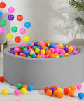 Colorful BPA-free plastic balls for ball pit in living room setting, 100pcs 2.2" set for toddlers, seven vibrant colors.
