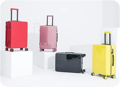 Four colorful suitcases on display, including red, pink, black, and yellow, each with handle extensions and caster wheels.