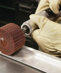 Worker using Combi S Wheel P180 Grit Aluminum Oxide with X Weight Backing on die grinder for metal finishing.