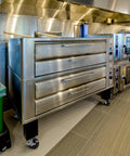 Commercial kitchen with stainless steel ovens and cooking equipment on tiled floor