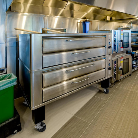 Commercial kitchen with stainless steel ovens and cooking equipment on tiled floor