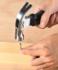 Compact 8oz magnetic claw nail hammer with an ergonomic non-slip handle being used to drive a nail into wood