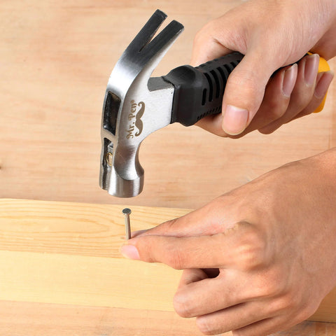 Compact 8oz magnetic claw nail hammer with an ergonomic non-slip handle being used to drive a nail into wood