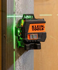 Compact self-leveling laser level with bright green cross lines and 360-degree planes mounted on a metal surface for precise alignment.