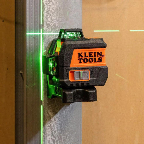 Compact self-leveling laser level with bright green cross lines and 360-degree planes mounted on a metal surface for precise alignment.