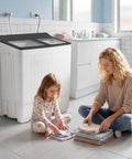 Portable Twin Tub Washing Machine With Drain Pump And Spinner Combo 18 Pound Washer And 8 Pound Spinner For 26 Pound Total Capacity Compact Laundry Unit For Apartments RVs Dorms Gray And White shown in a bathroom with a woman and child folding laundry.