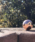Unique Metals Pure Copper Sphere 1-1/8" on wooden surface, ideal for healing, decorative use, or grounding in alchemical magic.