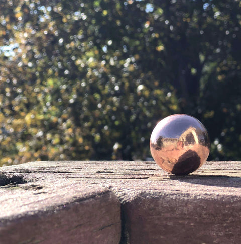 Unique Metals Pure Copper Sphere 1-1/8" on wooden surface, ideal for healing, decorative use, or grounding in alchemical magic.