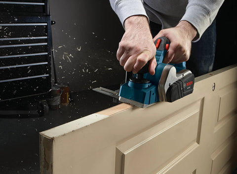 Renewed 120V corded planer delivers precise three and a quarter inch capacity for flattening and smoothing boards, 16,500 RPM, 6.5A performance, and includes stand with a dual-guide fence for accurate surfacing, door trimming, and stock prep in shops; tool shown planing a wooden door.