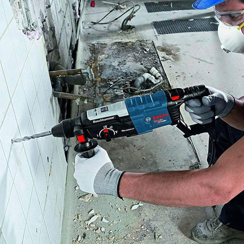 Worker using powerful 8.5 Amp corded SDS-Plus rotary hammer with 2.4 ft-lbs impact energy for drilling in masonry wall; renewed tool.