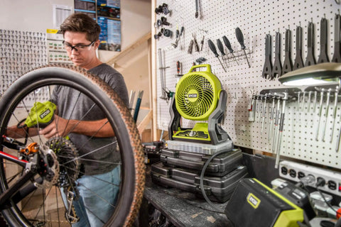 Cordless 18V Hybrid Whisper Series 7.5 Inch Fan Tool Only Bare Tool For Lawn Care Pros on workbench next to bike mechanic