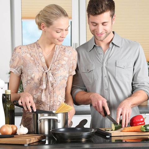 Man and woman cooking in modern kitchen, using cutting boards with kitchen tools and appliances visible on counter.