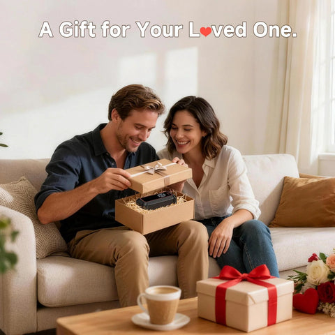 Couple opening gift box on sofa with cordless tire inflator portable air compressor inside, coffee table in foreground.