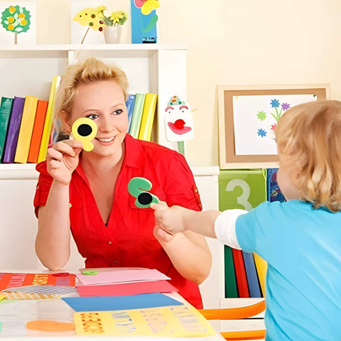 Child interacting with teacher using colored shapes in bright classroom setting with colorful books and decorations in the background.