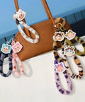 Crybaby Wild But Cutie Series phone charm blind box wrist straps in multiple colors attached to a handbag, PVC/ABS/nylon materials.