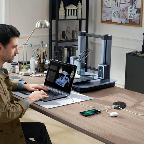 Person working at desk with laptop next to Desk Grommet 2 Inch (50 mm) 8 Pieces, Desk Hole Cover for Cables Black, in use on wooden table.