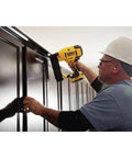 Worker using DEWALT 20V MAX cordless 18GA brad nailer kit with adjustable depth on wooden trim