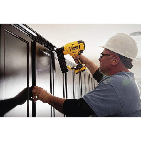 Worker using DEWALT 20V MAX cordless 18GA brad nailer kit with adjustable depth on wooden trim