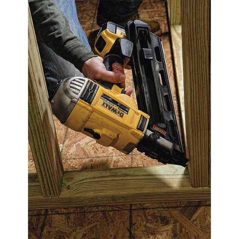 DeWalt 20V Max XR cordless framing nailer kit in use on a wooden frame at a construction site, showing the brushless motor and dual speed control.
