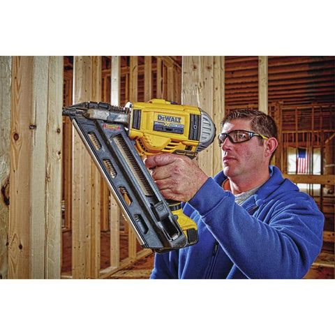 Construction worker using a DeWalt 20V Max XR cordless framing nailer kit in a wooden frame construction site, close-up view.