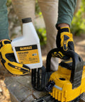 Person holding Eco Friendly Biodegradable Bar And Chain Oil For Chainsaws From DeWalt near a chainsaw