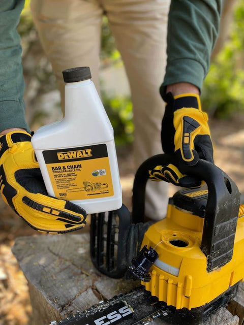 Person holding Eco Friendly Biodegradable Bar And Chain Oil For Chainsaws From DeWalt near a chainsaw