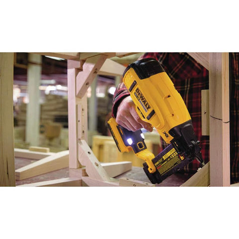 Person using DEWALT 20V MAX cordless 18GA brad nailer kit with LED work light on wooden frame for precise nail placement