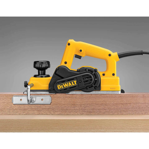 Side view of DEWALT 3-1/4 Inch Hand Planer Kit with a 5.5 Amp motor, trimming wood with carbide blades for precise edge shaving.