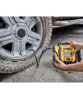 Person using DEWALT Tire Inflator Portable Air Compressor 20V MAX, Car Air Pump with Automatic Shut Off on a car tire