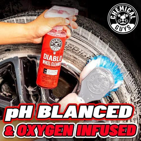 Hand holding Diablo Wheel Cleaner Spray Two Pack 16 Oz Bottles near a wheel, with brush cleaning tire, text 'pH Balaced & Oxygen Infused.'