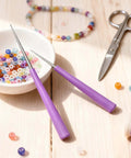 Diamond Tipped Bead Reamer Kit For Jewelry Making 2 Piece Set with pink handles beside colorful beads and scissors.