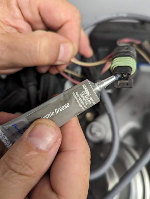 Applying Permatex 81150 Dielectric Tune-Up Grease, 0.33 oz. Tube, Silver to an automotive electrical connection.