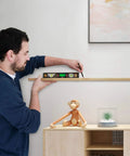 Person using a digital level with 11.5 inch LCD display and 360 degree inclinometer for vertical and horizontal angles on a shelf.