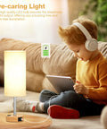 Child using tablet next to Bedside Table Lamp With 3 Way Dimmable Touch Control, USB C Charging Ports And AC Outlet, wood base, flaxen shade.