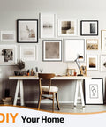 Gallery wall with various framed artwork above a wooden desk in a home office setting.