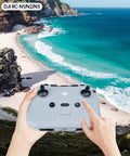 Pair of hands holding DJI RC-N1 remote controller with ocean view backdrop