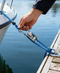 Boat secured with blue rope and stainless steel hook near a dock.