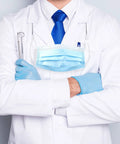 Doctor in white coat with blue tie and gloves, holding dental tools, wearing a mask and stethoscope.