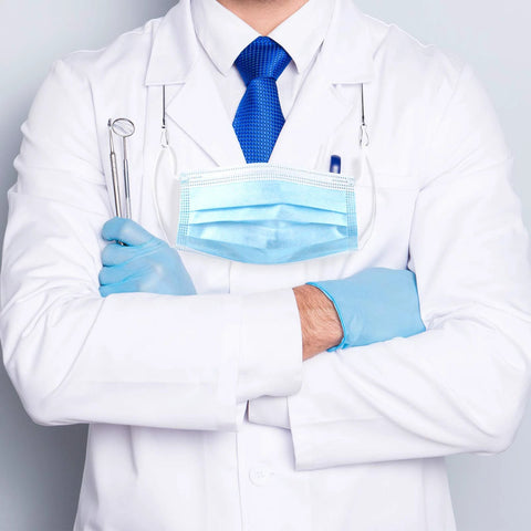 Doctor in white coat with blue tie and gloves, holding dental tools, wearing a mask and stethoscope.