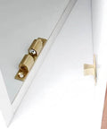 Brass spring detent latch on white cabinet door, angled view for precise positioning, indexing, locking in mechanical equipment.