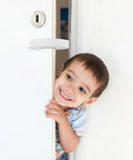 Child smiling near door with Door Pinch Guard Baby Door Stopper 6 Pack Soft Foam Keeps Tiny Fingers Safe and Doors From Slamming installed