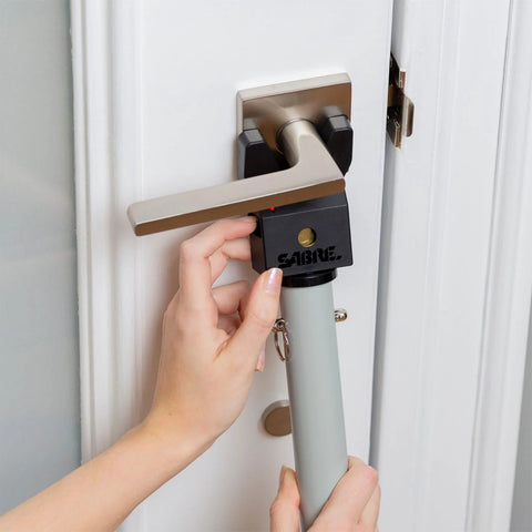 Adjustable Door Security Bar With Vibration Detecting Alarm And 115 Decibel Siren That Emits Up To 1100 Feet For Hinged And Sliding Doors Rubberized Foot For Strong Grip Collapsible Design For Easy Storage And Indoor Use Only installed on a door handle.