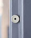 Close-up of installed Six Pack Replacement Door Silencer Set With Twelve Pieces For Metal Door Frames Ideal For Commercial Interior And Exterior Use Reducing Noise And Absorbing Shock Durable Weather Resistant Construction on a grey door frame.