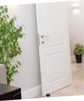 Image of a white door with a two piece door silencer set cushions door impact, protects walls and hardwood floors, prevents knob damage with no drilling, easy install anti collision stopper for quieter, safer living spaces, installed at the base, surrounded by home decor.